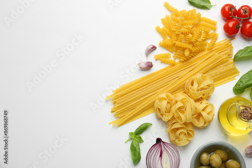 Different types of pasta, spices and products on white background, top view. Space for text