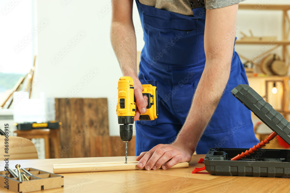 Craftsman working with drill at wooden table in workshop, closeup Craftsman working with drill at wooden table in workshop, closeup