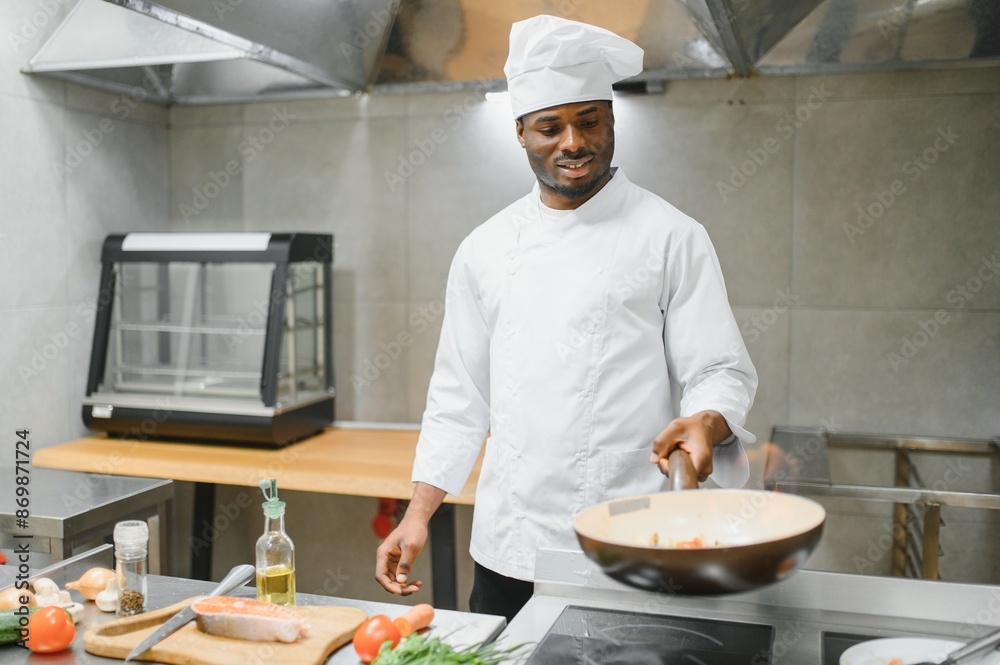 Portrait of happy African American male chef standing in restaurant kitchen Portrait of happy African American male chef standing in restaurant kitchen
