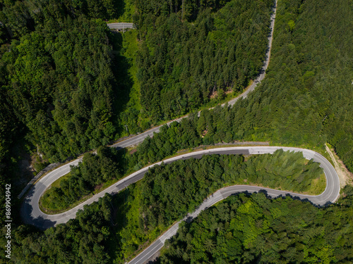 Beautiful aerial view of dense forest mountain landscape in summer time with curvy road cutting through forest. Aerial view by drone . Romania