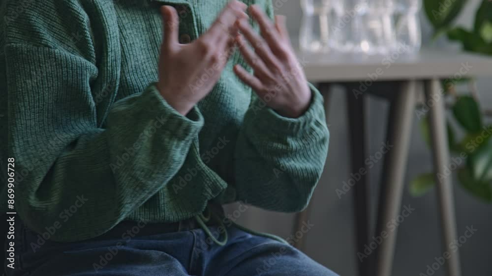 Cropped side shot of gesticulating hands of anonymous woman in green hoodie and jeans sharing her psychological problems with offscreen therapist during therapy session indoors