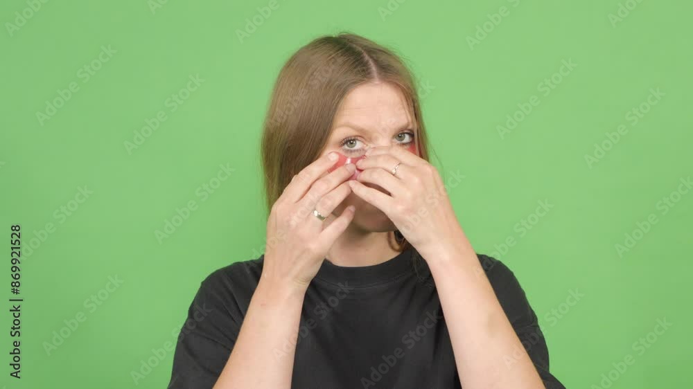 Slow motion. Woman takes on under-eye patches on a green background Slow motion. Woman takes on under-eye patches on a green background