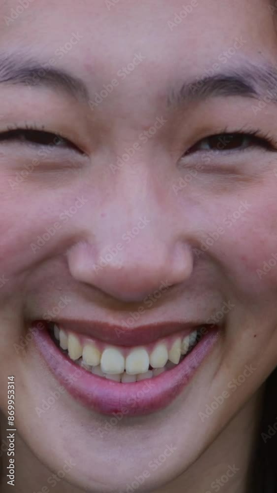 Close up portrait of young asian woman smile outdoors. Happy millennial chinese female looking at camera standing at city park. Vertical HD video. Positive people concept.