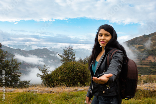 Hermosa foto de una feliz viajera hispana con una mochila en la cima de montañas verdes.cielo dia.Concepto de viaje turismo.
 photo