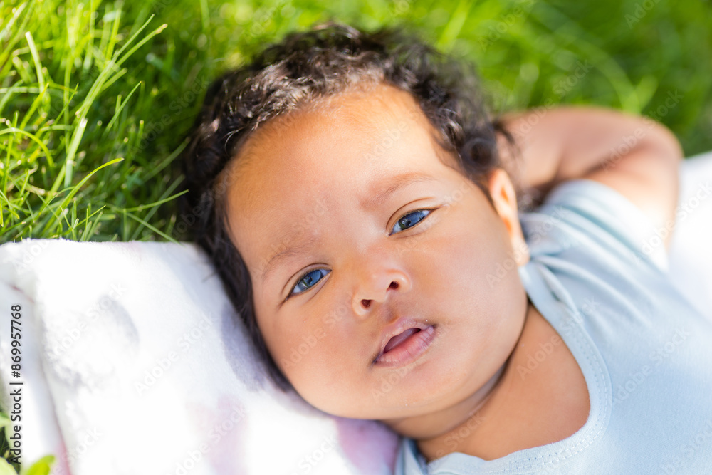baby African-American girl in a bodysuit lies on the lawn in summer baby African-American girl in a bodysuit lies on the lawn in summer