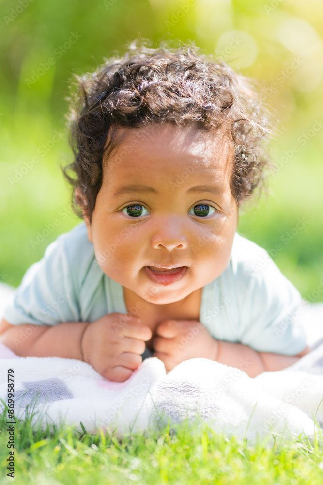 baby African-American girl in a bodysuit lies on the lawn in summer baby African-American girl in a bodysuit lies on the lawn in summer
