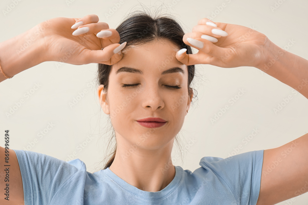 Naklejka premium Beautiful young woman doing face building exercise on beige background