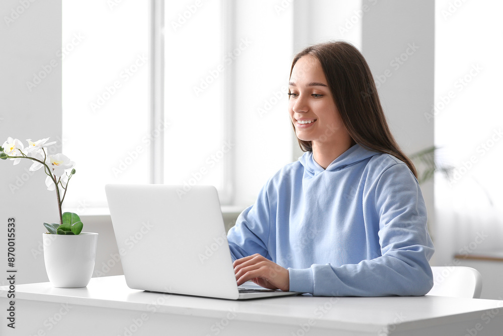 Young happy woman sitting at table and using laptop in stylish room Young happy woman sitting at table and using laptop in stylish room