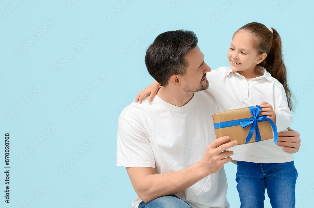 Daughter giving her father present on blue background. Father's Day celebration Daughter giving her father present on blue background. Father's Day celebration