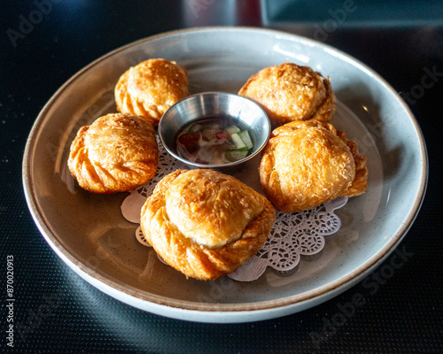Obraz na płótnie Golden-brown pastry parcels filled with spiced potatoes, peas, and tender chicken, baked to crispy perfection. Bursting with aromatic curry flavors, a delightful fusion snack for any occasion w salonie