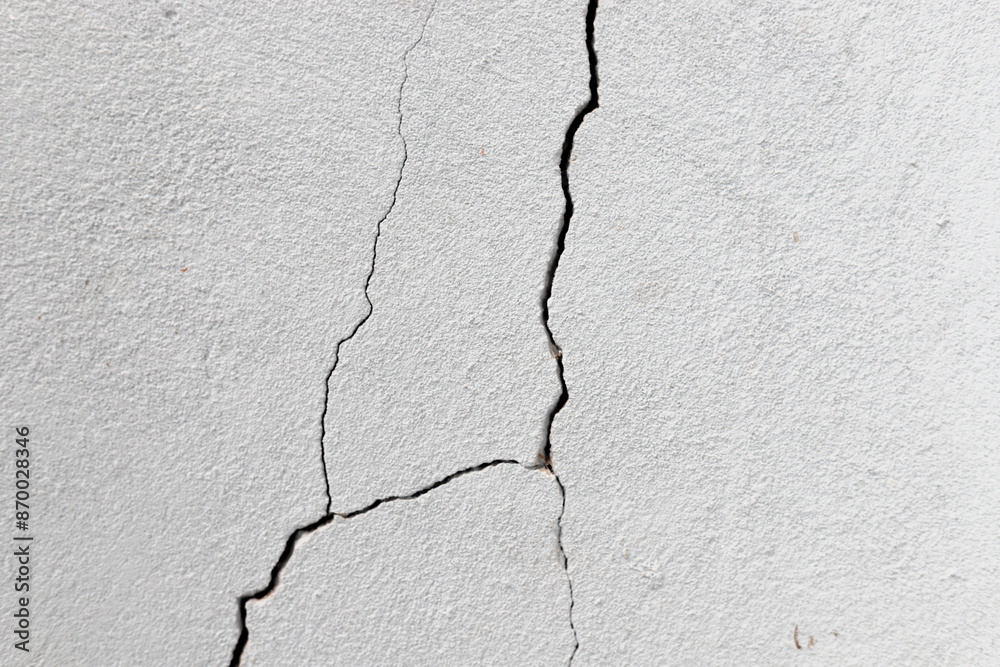 Obraz premium Crack in the wall. Cracks can be caused by soil movement, inadequate structural load, climate variations, natural wear and tear and even construction errors.