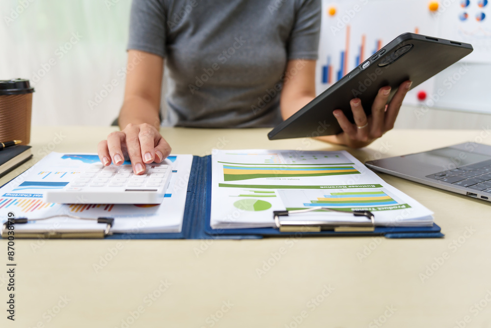 A housewife in a grey t-shirt works from home at a desk with a whiteboard, managing financial tasks like accounting, auditing, and financial advisory services with professionalism and dedication. A housewife in a grey t-shirt works from home at a desk with a whiteboard, managing financial tasks like accounting, auditing, and financial advisory services with professionalism and dedication.