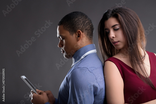 Jealous woman peers over man's internet browsing suspiciously photo