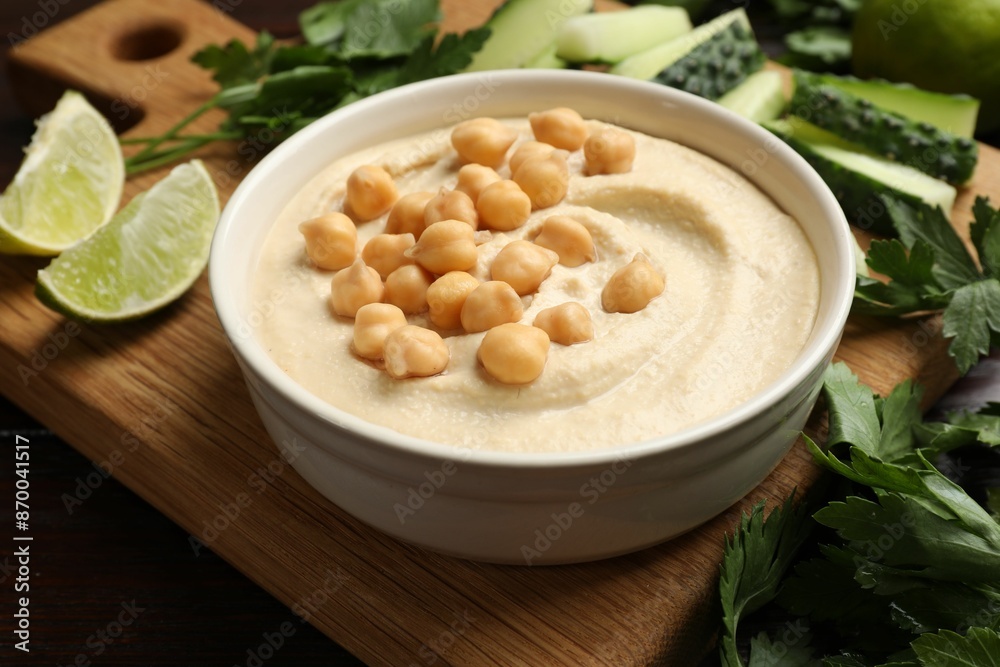Tasty hummus with chickpeas in bowl and fresh products on table, closeup Tasty hummus with chickpeas in bowl and fresh products on table, closeup