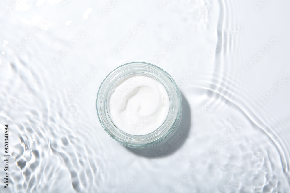 Cosmetic product. Jar with cream in water on light background, top view