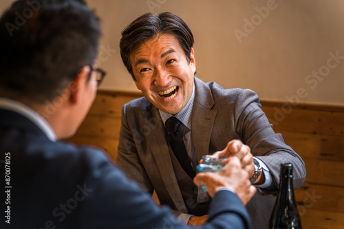 居酒屋・飲み屋でお猪口で乾杯するサラリーマン（酔っ払い・からみ酒）
