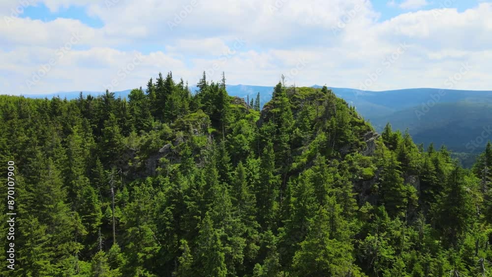Towering rock formations stand amidst a lush green forest under a clear sky in Saxon Switzerland Mountains range in Germany. Towering rock formations stand amidst a lush green forest under a clear sky in Saxon Switzerland Mountains range in Germany.