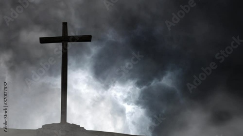 silhouette of a wooden cross against a background of storm and black clouds.