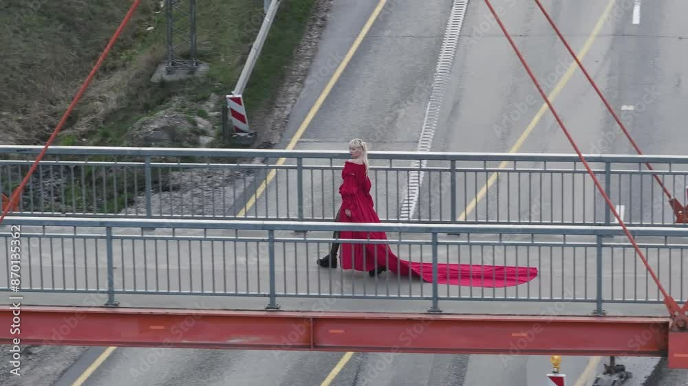 Aerial shot of a person walking with vibrant red dress walking across the bridge. Aerial shot of a person walking with vibrant red dress walking across the bridge.