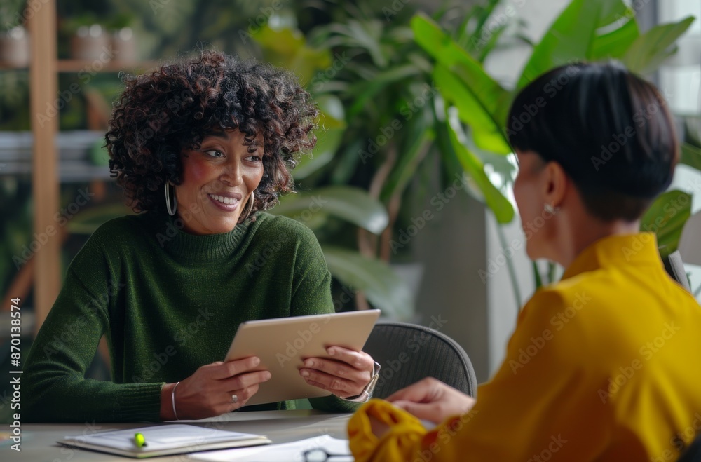 Two diverse women collaborating in a modern office environment with digital devices