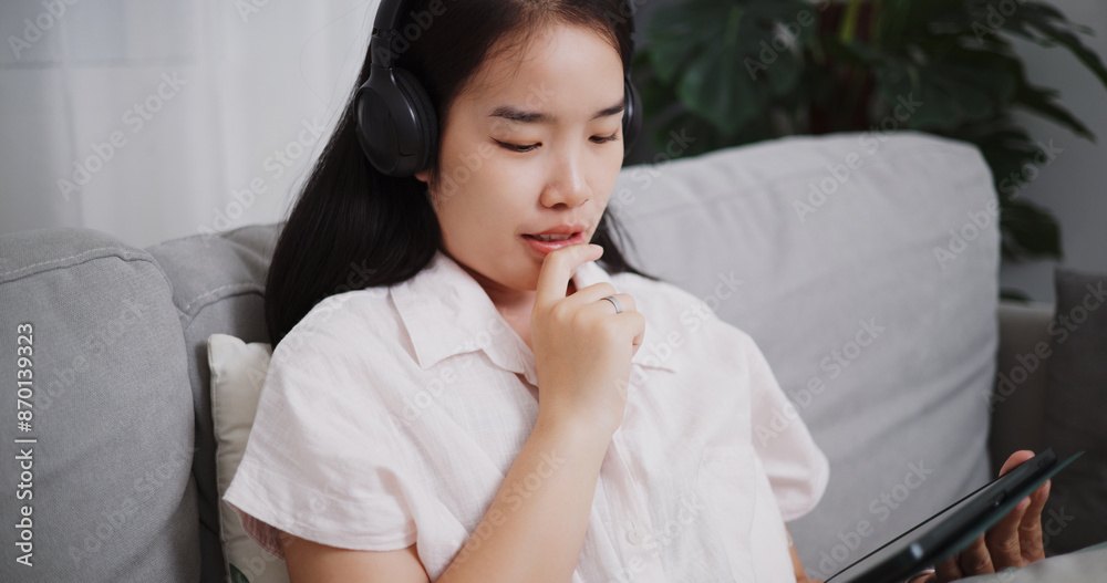 High angle view, Carefree young woman wear wireless headphone playing video game online with digital tablet on sofa at home ,Lifestyle with device technology High angle view, Carefree young woman wear wireless headphone playing video game online with digital tablet on sofa at home ,Lifestyle with device technology