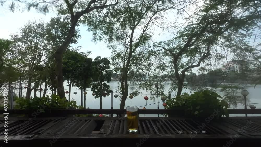 A glass of cold beer on a balcony. Glass of beer on a balcony bench. Traditional Bia Hoi Vietnamese beer over looking Truc Bach lake. Ha Noi, Vietnam.