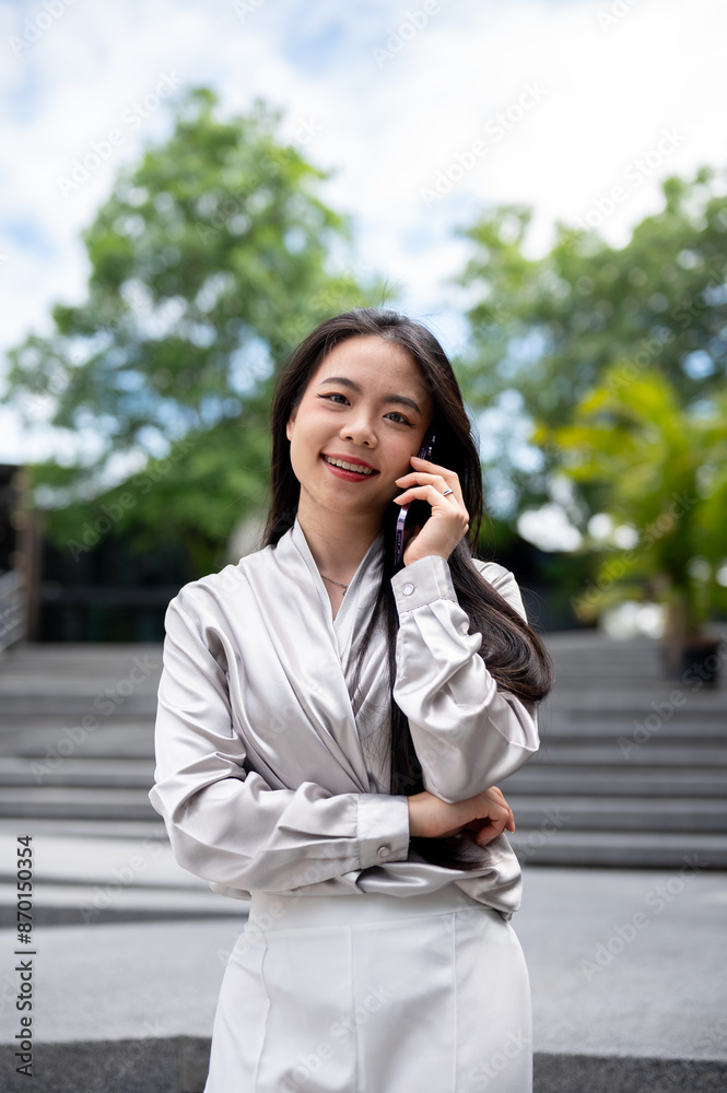 A businesswoman is talking on the phone with her client while walking down the stairs outdoors. A businesswoman is talking on the phone with her client while walking down the stairs outdoors.