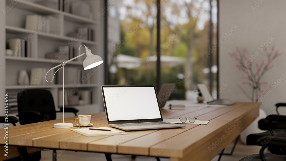 A laptop computer with a white-screen mockup on a wooden meeting table in a modern meeting room.