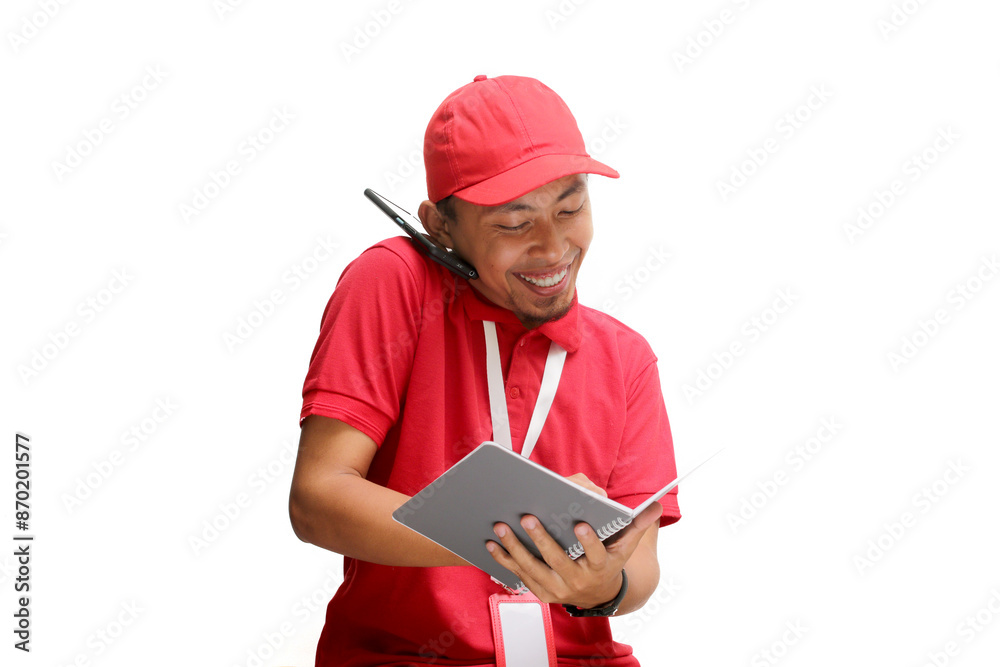 Excited Asian delivery man or courier having an engaging phone call with a customer while taking notes on a notebook. Isolated on a white background Excited Asian delivery man or courier having an engaging phone call with a customer while taking notes on a notebook. Isolated on a white background
