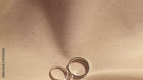 Dropping a pair of engagement rings made of platinum and diamonds on a cloth laid on a table.