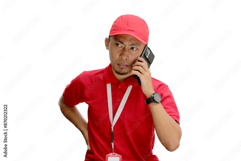 Annoyed Asian delivery man or courier talking on his phone, handling issues such as bad or incomplete addresses, customer complaints, or problems with delivery. Isolated on a white background. Annoyed Asian delivery man or courier talking on his phone, handling issues such as bad or incomplete addresses, customer complaints, or problems with delivery. Isolated on a white background.