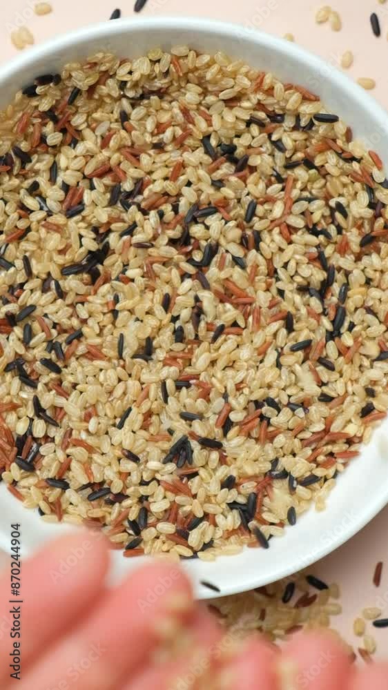 Hands pour raw uncooked rice cereals, into a plate. Vertical Slow Motion Hands pour raw uncooked rice cereals, into a plate. Vertical Slow Motion
