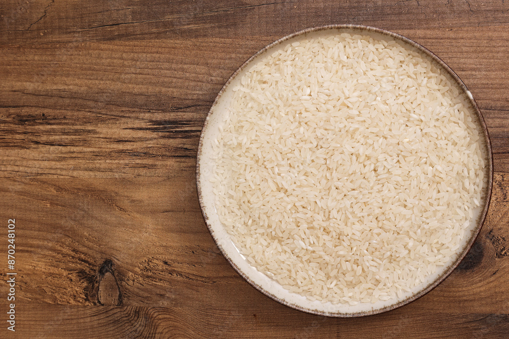 A bowl filled with rice on a wooden table, highlighting the natural texture and simplicity of the grain. A bowl filled with rice on a wooden table, highlighting the natural texture and simplicity of the grain.