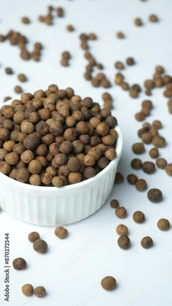 Close-up of black peppercorns in a plate on a white background Close-up of black peppercorns in a plate on a white background