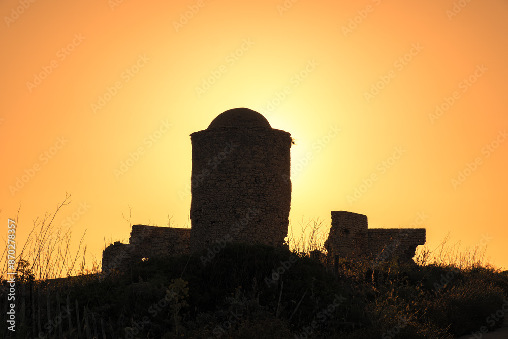 Obraz premium Golden sunrise behind a derelict ancient stone windmill on the cliffs at Bonifacio in Corsica