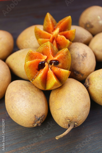 Beautifully Cut Sapodilla Fruit on Heap of Whole Fruits photo