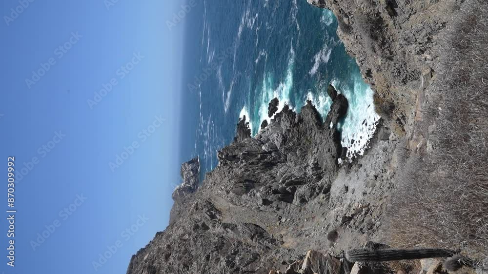 Vertical shot of Punta Lobos, waves crashing against rocky sea cliffs in the middle of the day near Todos Santos, BCS, Mexico