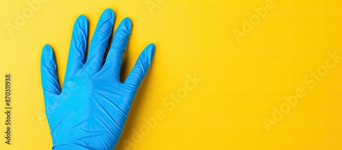 Blue protective glove on yellow background with copy space image.