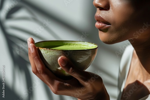 Beautiful african american woman holding cup of vibrant green tea matcha on a clean background. Traditional nutrient rich warming drink. Slow living, enjoying a break, perfect morning, relaxing photo