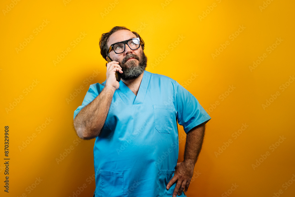 Doctor in blue coat on yellow background using a smartphone. Doctor in blue coat on yellow background using a smartphone.