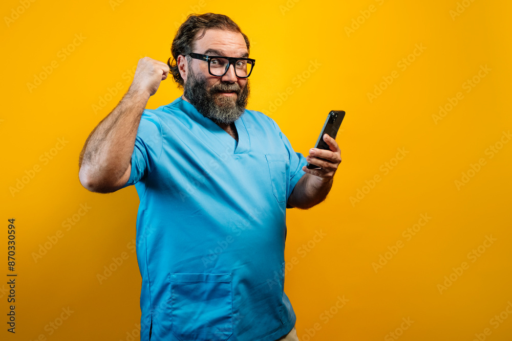 Doctor in blue coat on yellow background using a smartphone. Doctor in blue coat on yellow background using a smartphone.