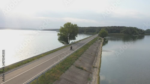 Wallpaper Mural Aerial shot of biker ride on motorbike through road near lake. Motorcyclist racing his motorcycle at dam route on summer day. Man drive bike through bridge of river or pond. Concept of travel.Top view Torontodigital.ca