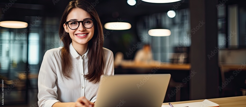 Fototapeta premium Portrait of a cheerful young businesswoman at her desk with a laptop, promoting online teaching for remote education with copy space image.