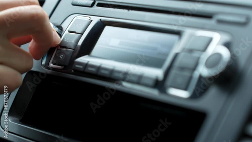Woman hand turning on car radio, close-up. Driver pressing car radio system