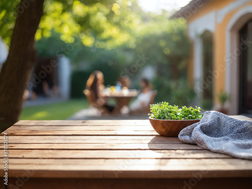 Wooden tabletop with greenery and a blurred backyard gathering photo