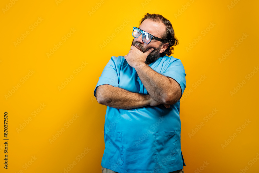 The doctor in a blue coat on a yellow background and thoughtful. The doctor in a blue coat on a yellow background and thoughtful.