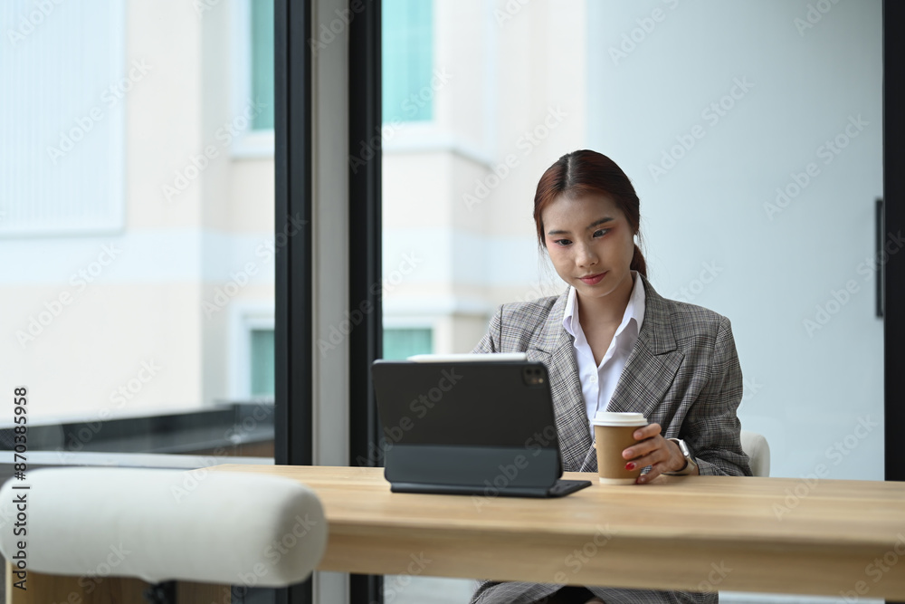 Beautiful Asian woman officer staff in formal suit using digital tablet in modern office Beautiful Asian woman officer staff in formal suit using digital tablet in modern office