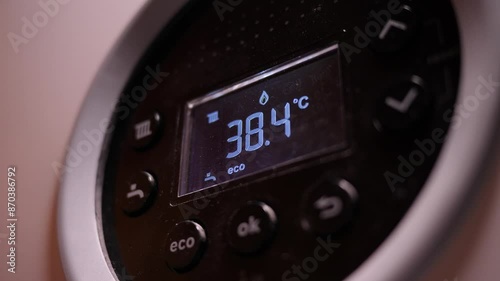 Digital thermostat display in a dimly lit room. Close up.