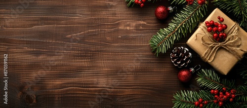 Wooden surface with fir tree branches, red berries, and a present box creating a festive Christmas and New Year background with copy space image.