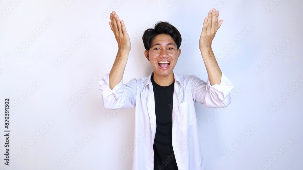 Excited young Asian man gestures pointing upwards using the palm of his hand Excited young Asian man gestures pointing upwards using the palm of his hand